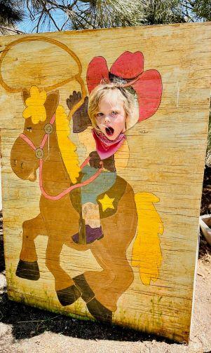 photo of little girl with face in cowgirl photo board